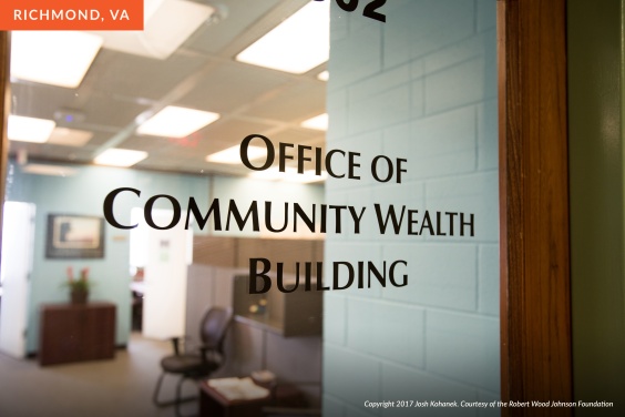Glass door of a government office with text on it reading Office of Community Wealth Building